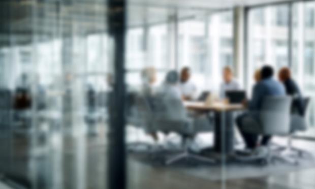An out-of-focus view of people in a meeting room.